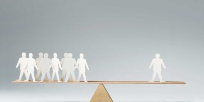 Men balanced on seesaw over a single man